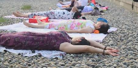 市民在鹅卵石地面做热疗,市民躺鹅卵石